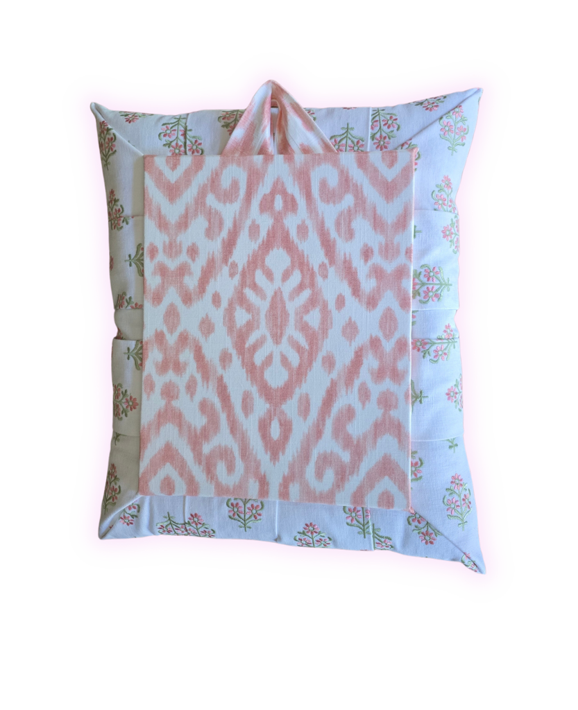 The back view of a floral overstuffed picture frame with a coordinating pink/white ikat pattern fabric on a white background.