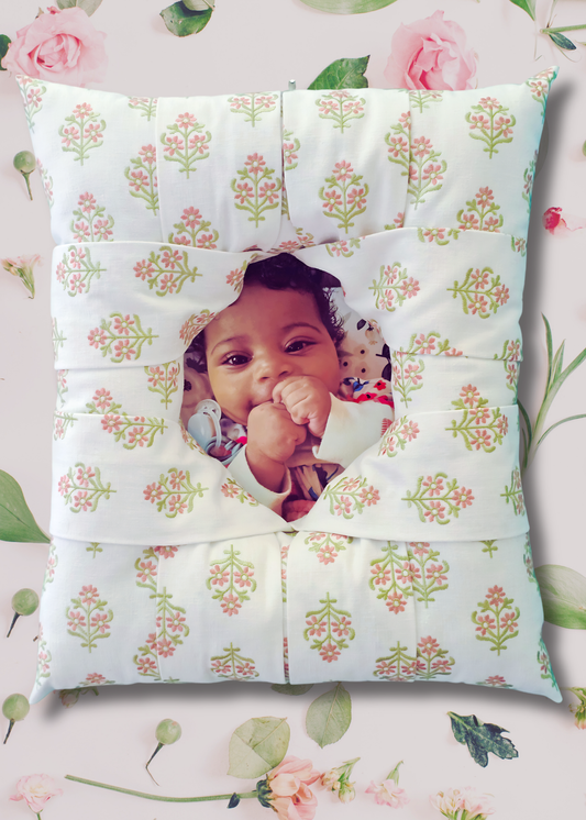 An overstuffed picture frame with  an embroidered pink and green floral pattern on a white background, featuring a custom photo cutout in the center showing a smiling baby. The frame is displayed on a light pink floral background.
