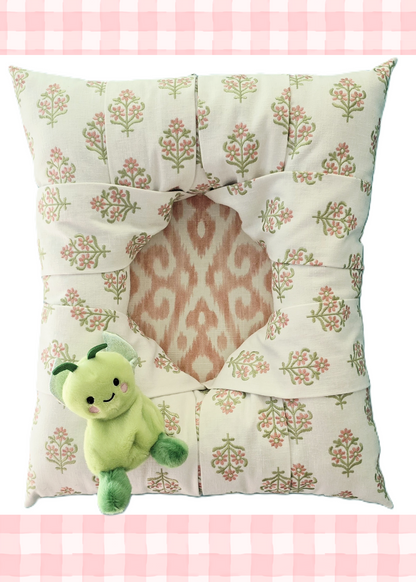 Full face view of an overstuffed picture frame in white fabric with embroidered floral motif in pink and green, showing the coordinating pink/white ikat patterned fabric covering the inside plate.