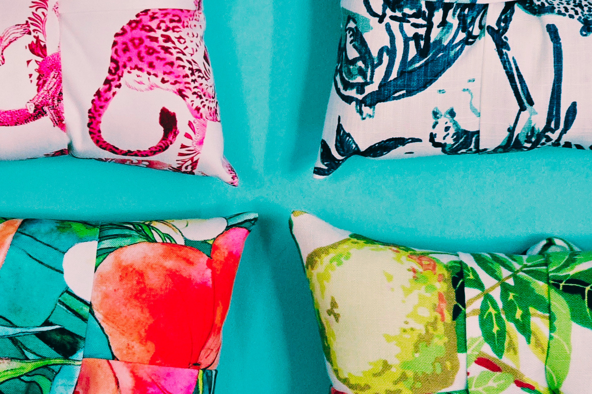 Four overstuffed luxe picture frames with vibrant tropical and animal prints arranged on a turquoise background.
